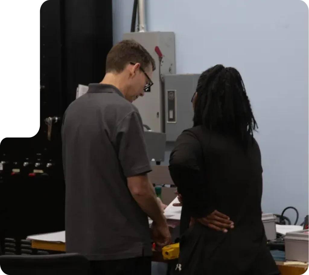 Two colleagues discussing documents in a technical workspace