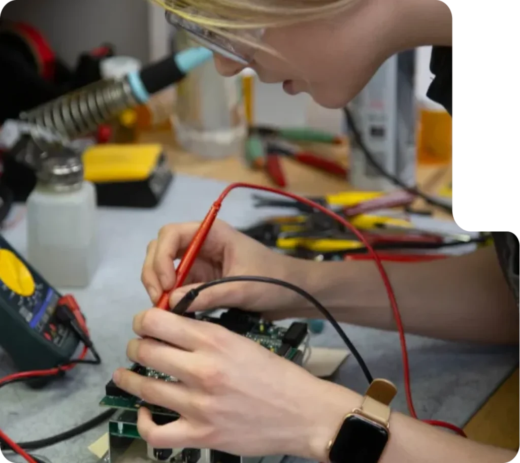 Engineer working on an electronic circuit board with measuring instruments and tools on the desk